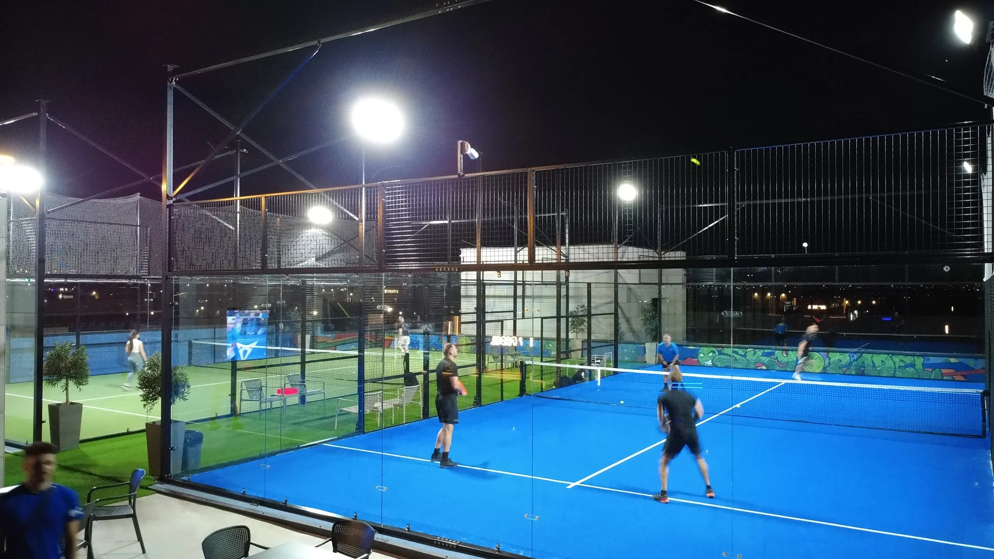 Players on the floodlit blue rooftop court