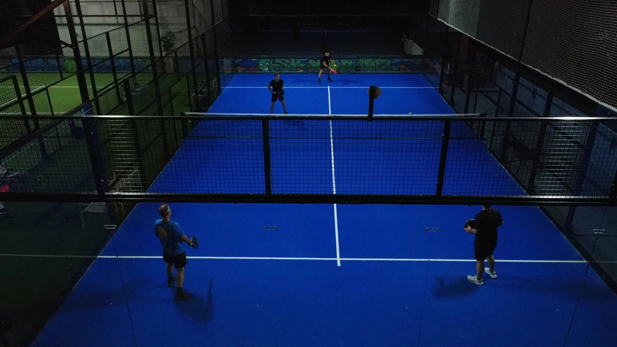 A doubles match on the blue court at night